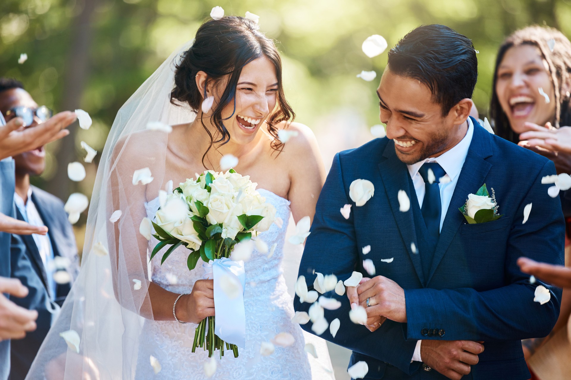 Guests throwing confetti over bride and groom as they walk past after their wedding ceremony. Joyful young couple celebrating their wedding day